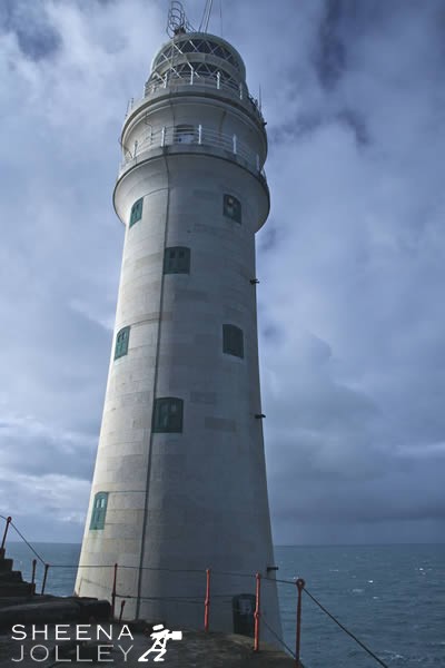 Portrait of Fastnet.jpg - Looking up at the Fastnet Rock from the helipad. Beyond is a stormy sky and an eerie light